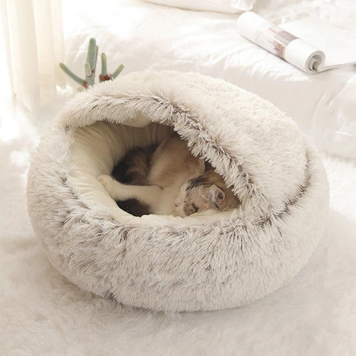 Light gray plush cave cat bed with fringe-lined entrance; cat sleeping inside